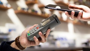 Woman paying with NFC technology on mobile phone in shop
